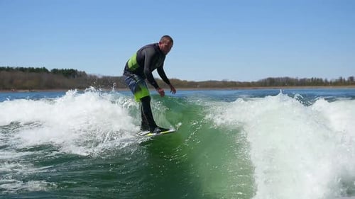 A man wake surfing behind a boat on a lake