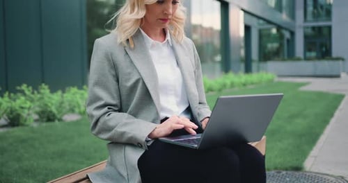 Mujer de negocios trabajando en un portátil sentado en el fondo del edificio de la ciudad de la calle