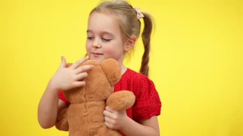 Happy Child Hugging Teddy Bear on Yellow Background
