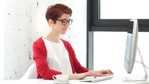 Young Woman Working in Office, Sitting at Desk, Using Computer and Looking on Screen