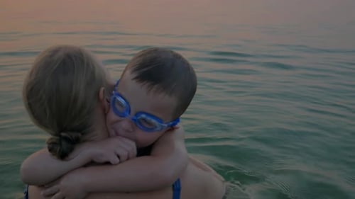 Hugs and kisses of mother with son in the sea