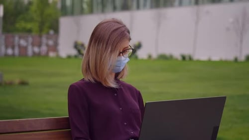 Woman portrait works on laptop outdoor sitting on park bench