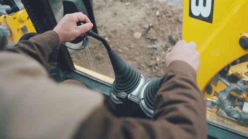 Man Operating Digger Machine Controls From Inside Cab