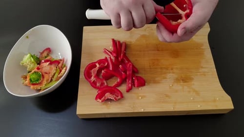 Hands slicing a bell pepper with knife