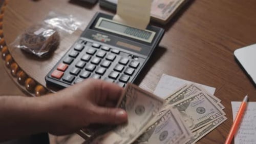 Counting Money Next to Calculator and Notes