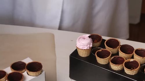Waffelkegel, innen mit flüssiger Schokolade bestrichen. Sie stehen auf Tribünen.