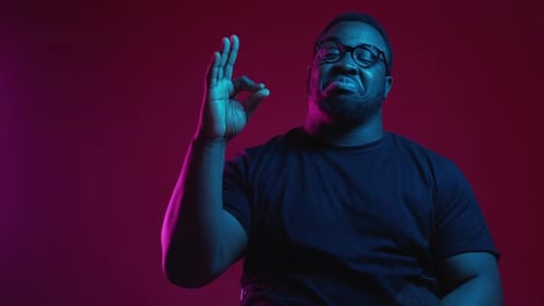 Stylish Man Gives OK Sign in Colorful Lighting