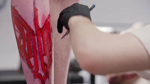 Tattoo Artist Tracing Leg Tattoo Design