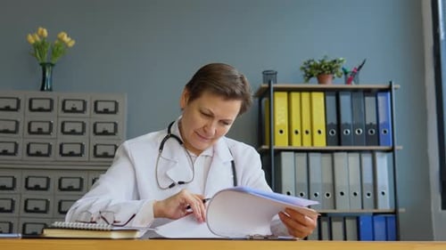 Female Doctor Reviewing Patient Records at Desk