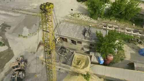 Crane Claw Loading Rubble into Conveyor at Concrete Factory