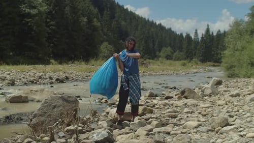 Voluntario árabe consciente del medio ambiente llevando una bolsa de basura con residuos de plástico en las montañas