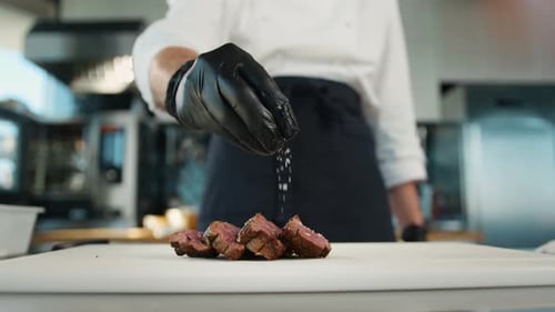 The chef sprinkles the filet mignon with coarse salt. Serving food in restaurant.