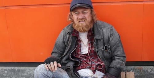 Person Sitting Next to Shopping Cart in Urban Setting