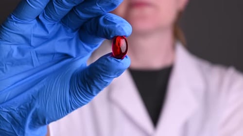 Gloved Hand Holding Red Pill