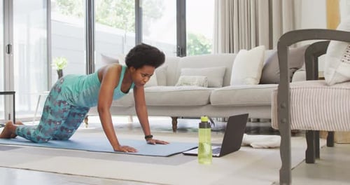 Happy african american wearing sportswear, exercising, using laptop