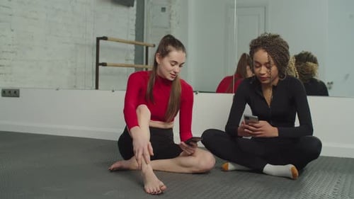 Sporty Women with Phones Relaxing After Workout at Gym
