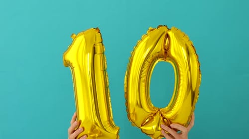 Gold Number Ten Balloon Against Blue Wall