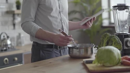 Man Cooking with Tablet in Kitchen