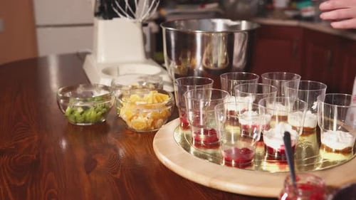 Konditorin streut zum Nachtisch Schlagsahne auf Tassen