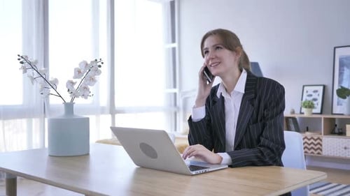 Business Woman Talking on Phone While Typing