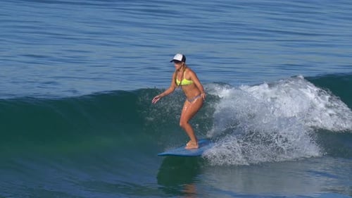 Blond Woman Surfing a Wave on Turquoise Board
