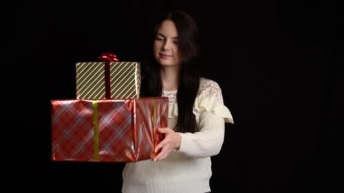 Woman Holds Christmas Presents Against Dark Background