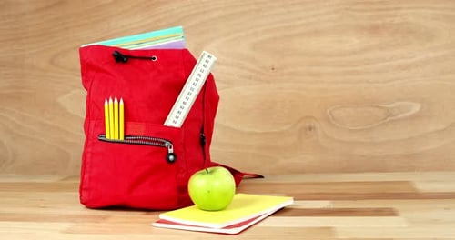 Close-up of school bag with books, apple and stationery