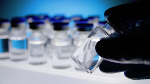 Gloved Hands Rotating Vial of Medicine for Research