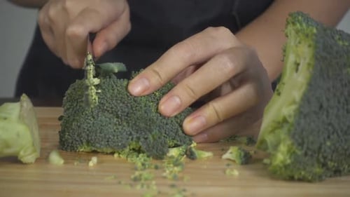 woman making salad healthy food and chopping broccoli on cutting board in the kitchen.