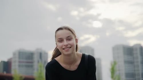 Smiling Young Woman Walking Towards Camera in City