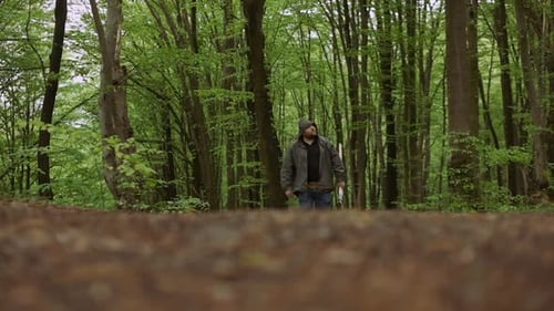 Casual Strong Man Walking with Ax in Wild Deciduous Forest.