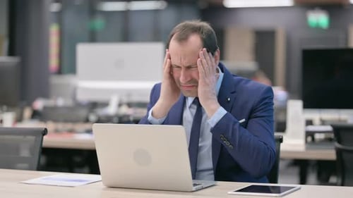 Stressed Businessman Using Laptop in Office