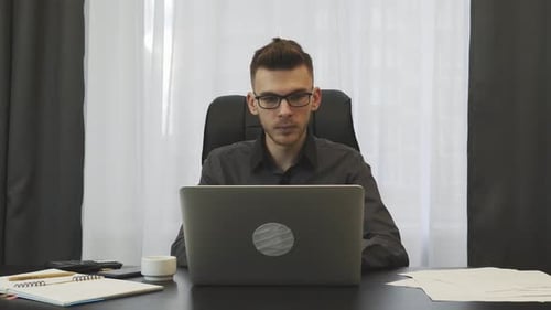 Confident Young Businessman Works on Laptop in Office
