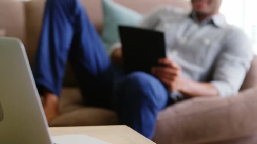 Happy man using digital tablet in living room