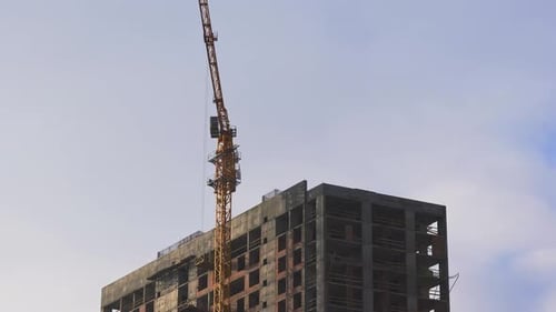 Construction tower crane working on the roof of skyscraper.