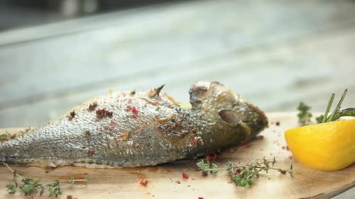 Grilled Fish with Lemon and Herbs on Wooden Board