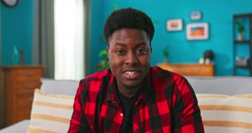 Young Man Talking Directly To Camera on Sofa