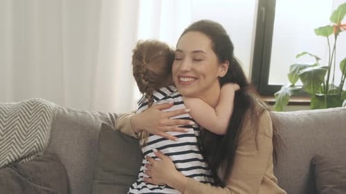 Happy Woman Hugging a Child on Sofa