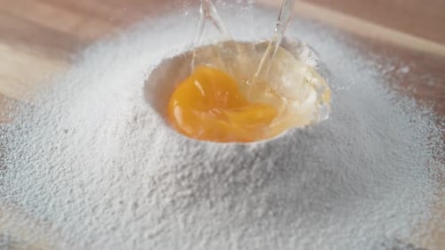 Egg falls on a pile of flour. Slow Motion.