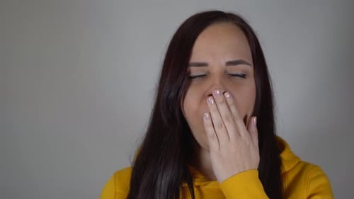 Une femme qui bâille sur fond gris