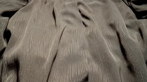 Detaillierte Stoffstruktur aus glänzendem grauem Stoff, der mit Dolly Shot in Makro-Nahaufnahme fließt