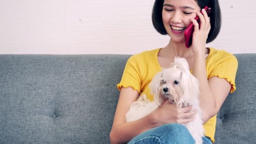 Woman Talking on Phone While Holding a Dog