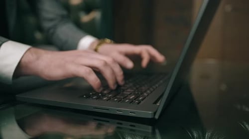 Businessman in Suit Is Sitting and Using Laptop Indoor