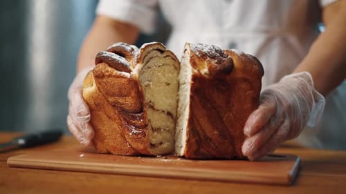Baker Separating Golden Brown Sweet Roll on Cutting Board