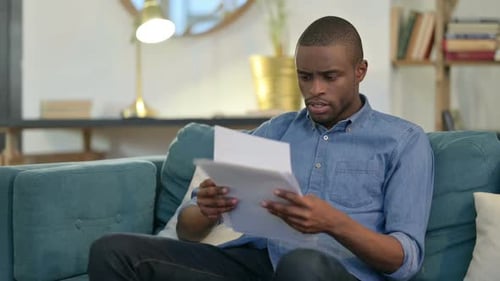 Man Reading Documents on Sofa at Home