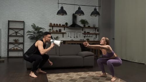 Woman Doing Squats as Man Yells Through Megaphone
