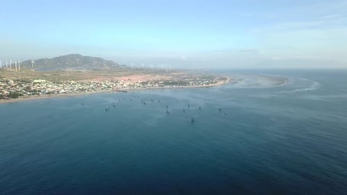 Aerial View of Small Village Shore with Colorful Fishing Boats on Turquoise Ocean.