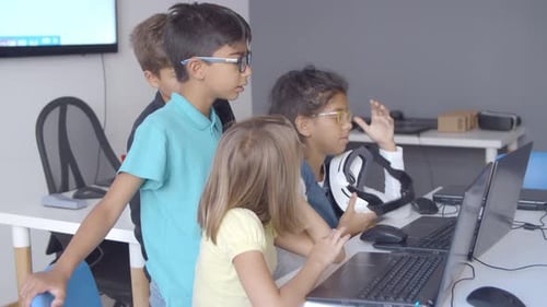 Group of Serious Schoolchildren Sitting and Standing at Desk
