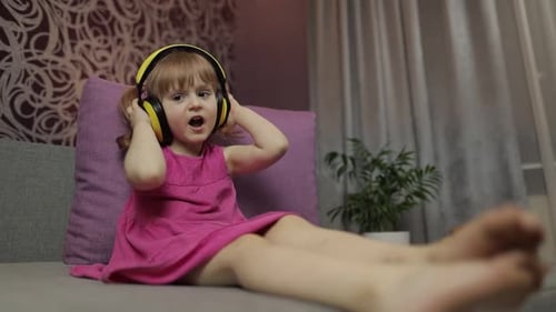 Child in Headphones Singing on Couch