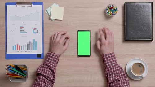 Top View of a Man's Hands Touch the Top Right Corner of a Green Screen on a Smart Phone